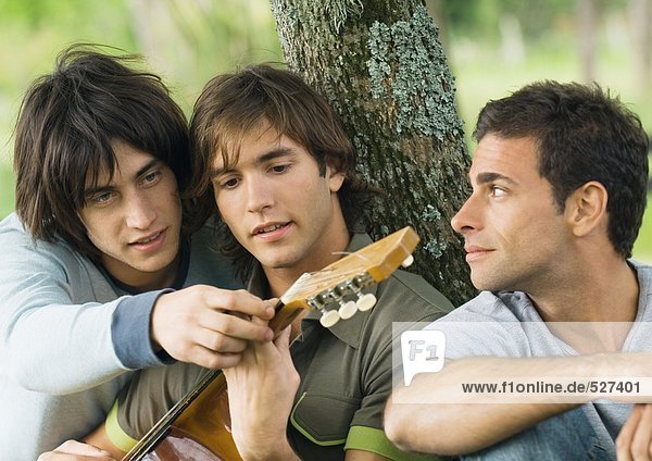 Junger Mann zeigt Freund-Hand-Position auf der Gitarre