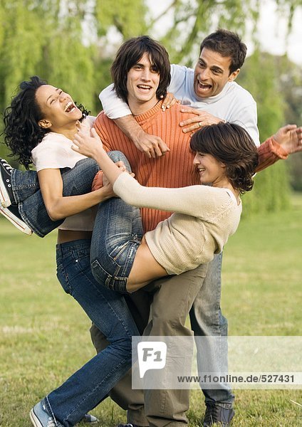 Young people jumping on friend playfully