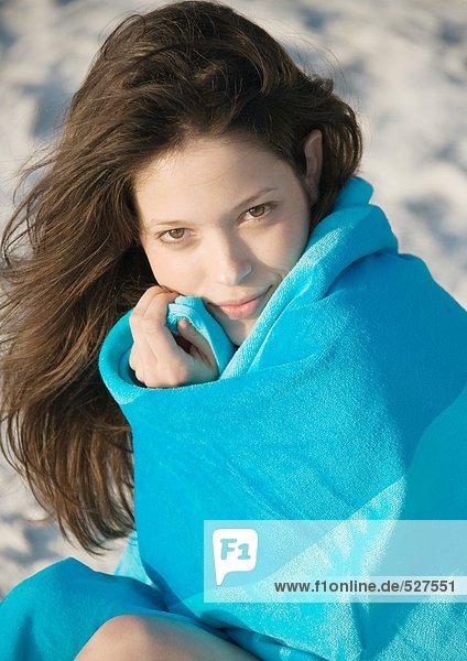 Junge Frau in Handtuch gewickelt am Strand