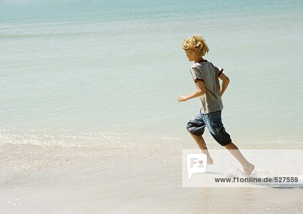 Junge rennt durch die Brandung am Strand