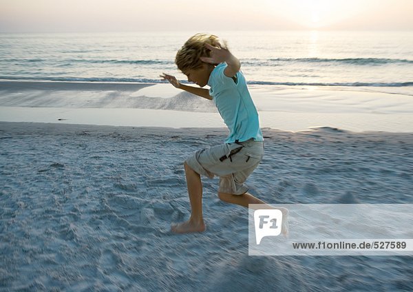 Junge springt am Strand  Seitenansicht