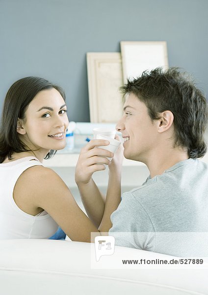 Couple sitting with arms linked  about to drink