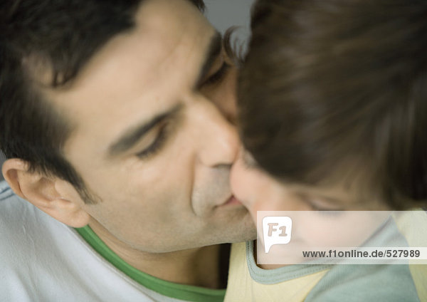 Vater küsst seinen Sohn auf die Wange  geschlossene Augen  Porträt  extreme Nahaufnahme  Unschärfe