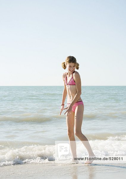 Girl standing in surf on beach