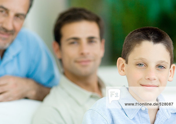 Boy  portrait with father and grandfather in background