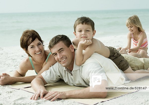 Familie am Strand liegend  lächelnd