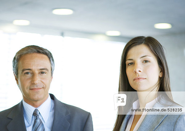 Mature businessman and young businesswoman  looking at camera