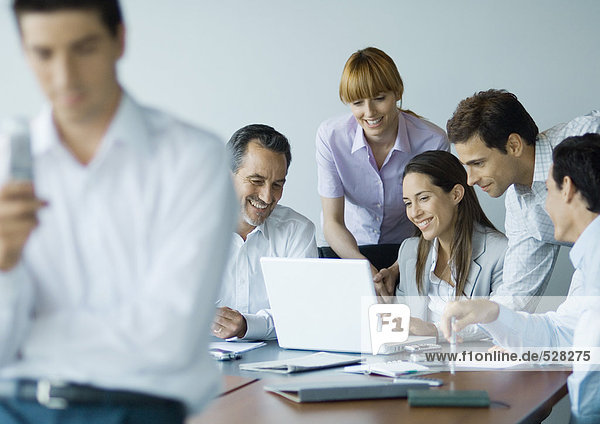 Business colleagues gathered around laptop  smiling