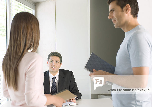 Couple speaking to businessman in office