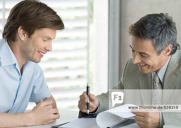 Young man with mature business man  looking at document