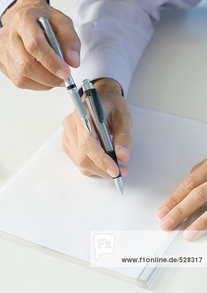 Geschäftsleute  die Stifte über Papier halten