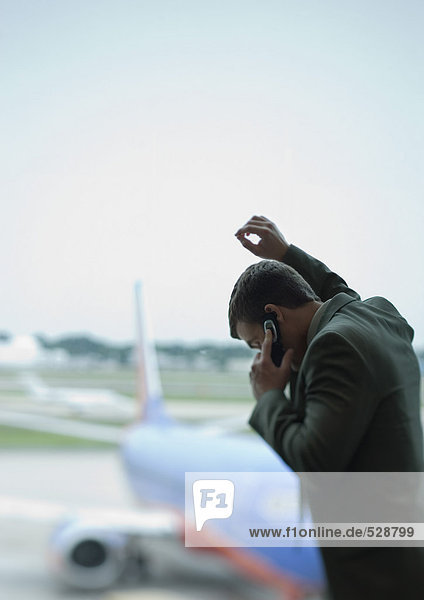 Mann telefoniert  Flugzeug im Hintergrund