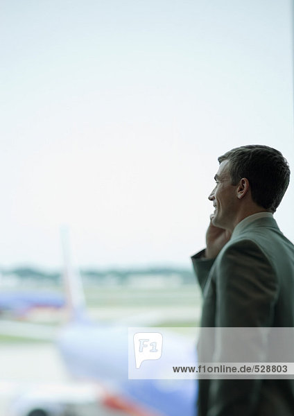 Mann mit Telefon  Flugzeug im Hintergrund