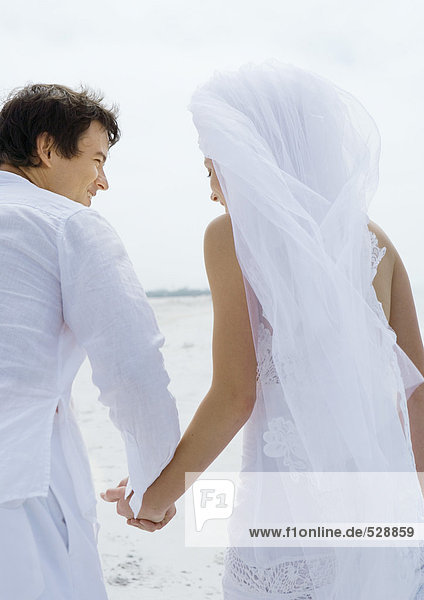 Braut und Bräutigam am Strand  Händchen haltend