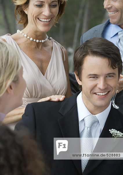 Hochzeitsfeier im Freien  junger Bräutigam mit Schwiegermutter im Hintergrund