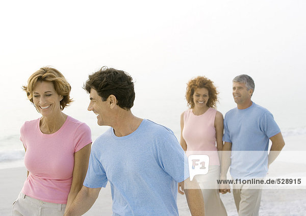 Two mature couples walking on beach