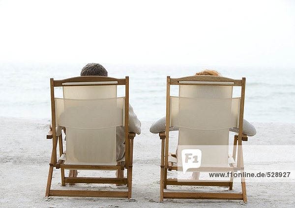 Two people sitting in beach chairs  rear view