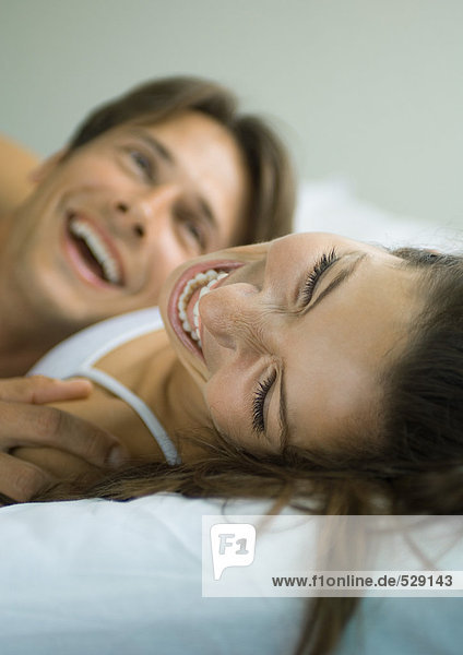Paar im Bett liegend  lachend