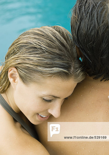 Paar in der Nähe des Swimmingpools  Frau liegt mit dem Kopf auf der Schulter des Mannes.