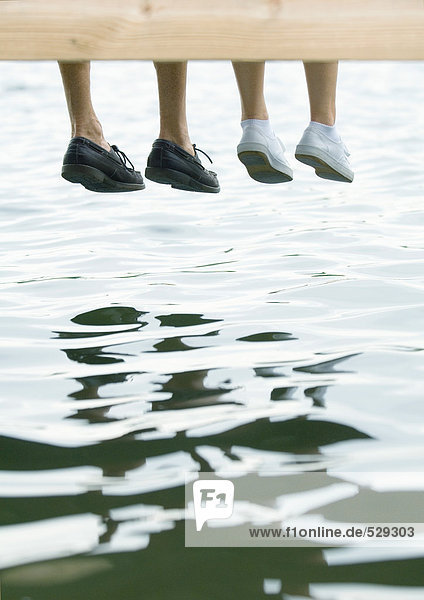 Two people sitting on dock  view of feet