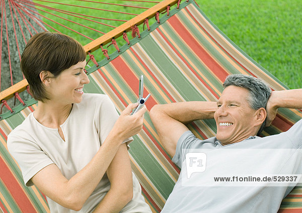 Couple in hammock  woman taking photo of man  with phone