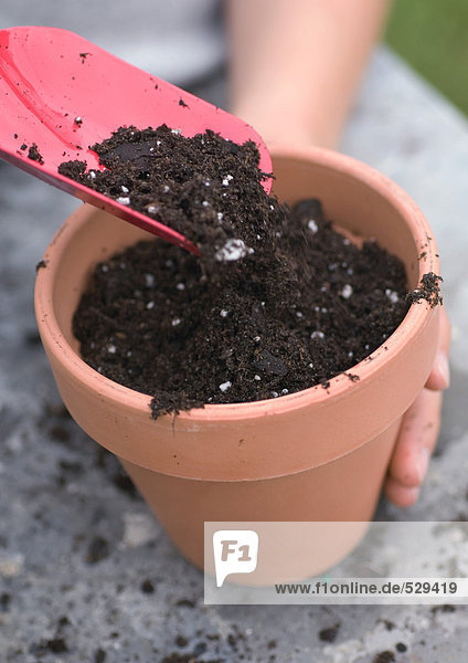 Using trowel to put soil into pot