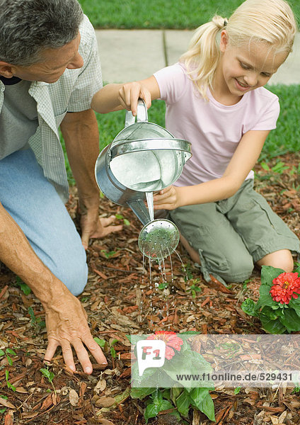 Man and girl watering flowers
