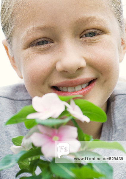 Mädchen lächelt mit Vinca-Pflanze