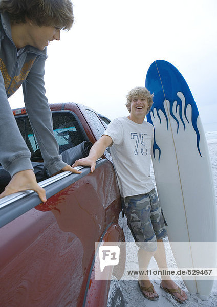Surfer steht neben dem Pickup-Truck