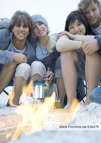 Junge erwachsene Freunde sitzen am Lagerfeuer