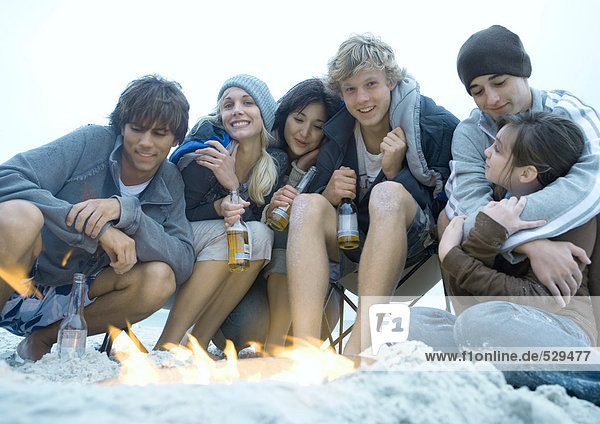 Gruppe junger erwachsener Freunde  die am Lagerfeuer sitzen
