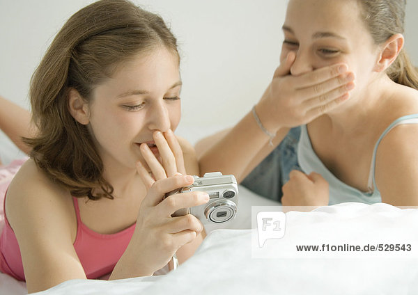 Zwei preteen Mädchen  die Digitalkamera betrachten  lachend und Mund bedeckend