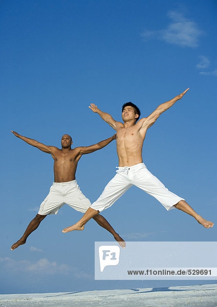 Two men jumping in the air with arms and legs out