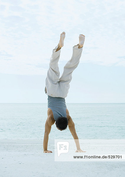 Man doing handstand on beach