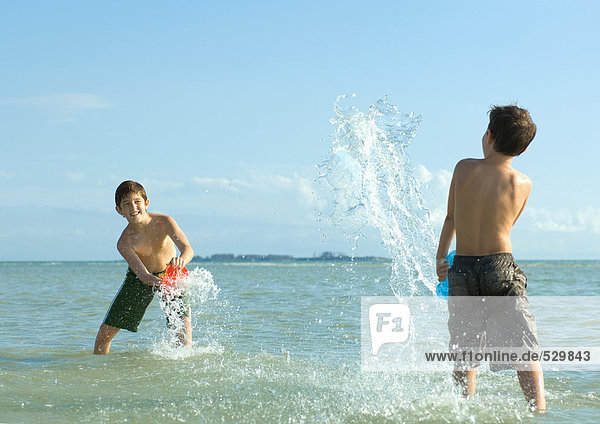 Zwei Jungen  die am Strand im Wasser planschen.
