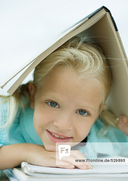 Girl holding book over head  smiling
