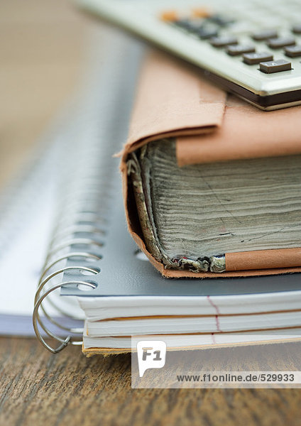 Stapel von Notebooks  Büchern und Taschenrechner