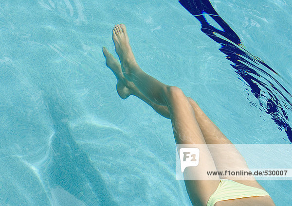 Frau schwimmt im Pool  Blick von der Taille abwärts