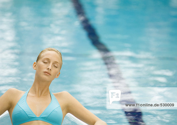Frau entspannt am Pool mit geschlossenen Augen