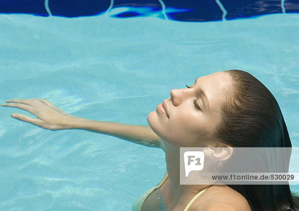 Frau im Pool stehend mit geschlossenem Kopf und geschlossenen Augen