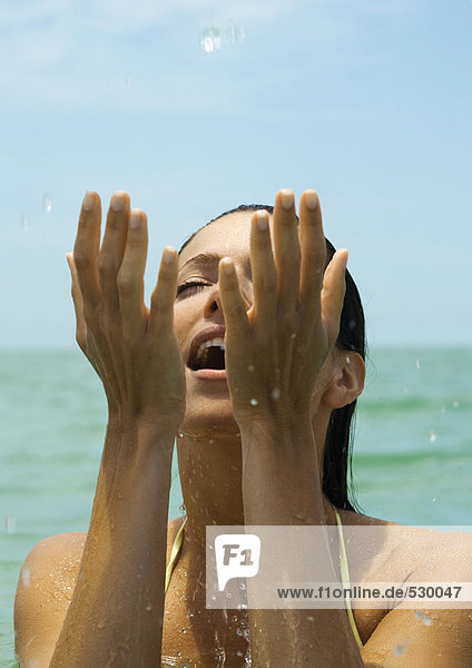 Frau im Wasser spritzend im Wasser Augen geschlossen