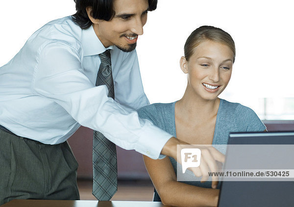 Businessman helping female colleague with computer