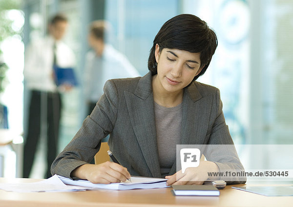 Geschäftsfrau am Schreibtisch sitzend  schreibend