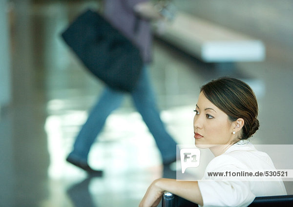 Frau sitzt in der Flughafenlounge