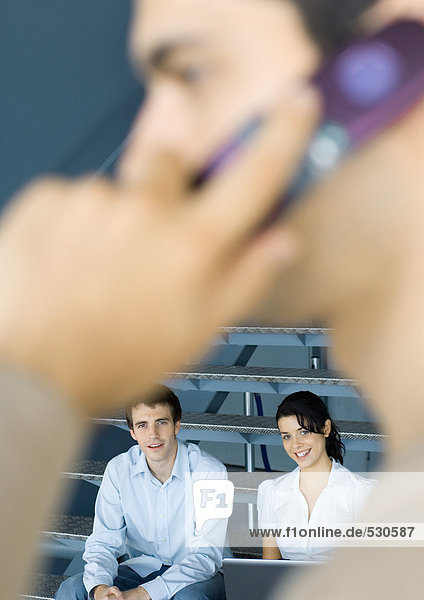 Young business professionals  man using cell phone in blurred foreground