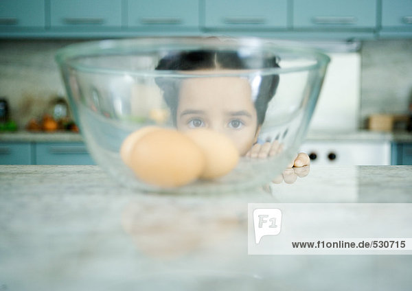 Mädchen schaut durch eine Schale mit Eiern