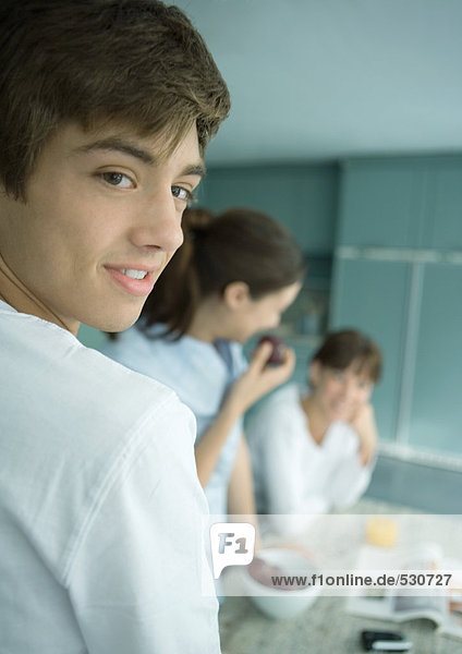 Teenager-Junge mit Familie in der Küche  über die Schulter schauend