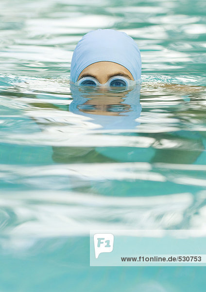 Person in swimming pool wearing bathing cap and goggles