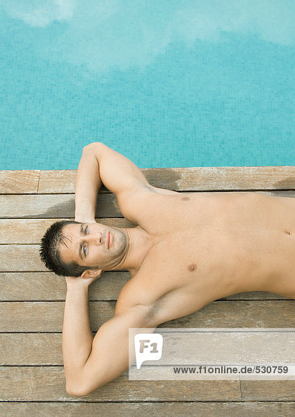 Man lying by side of swimming pool