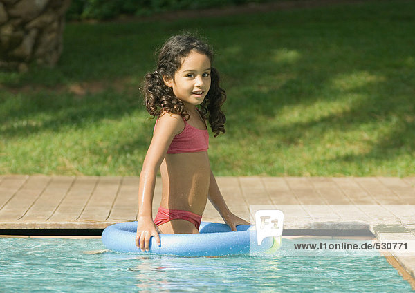 Little girl in swimming pool with floating ring